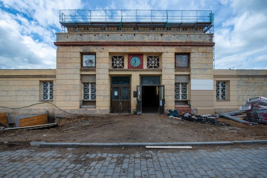 Uhr über den Eingangstüren und Gebäude mit abgeblättertem Putz
