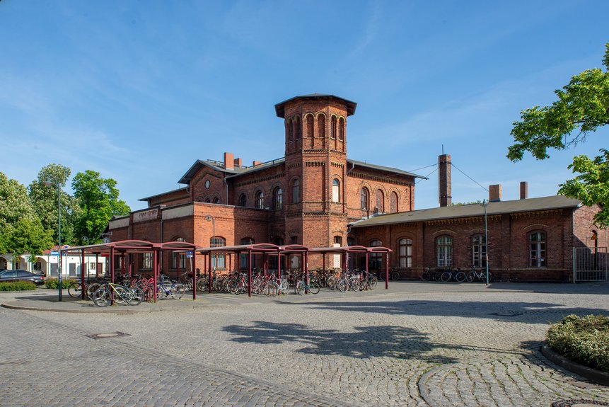 Seitenaufnahme vom Bahnhofsgebäude mit dem Fahrradparkplatz im Vordergrund
