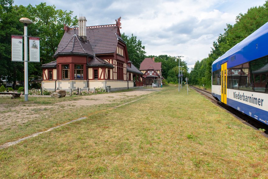 Zug hält vor dem Bahnhofsgebäude