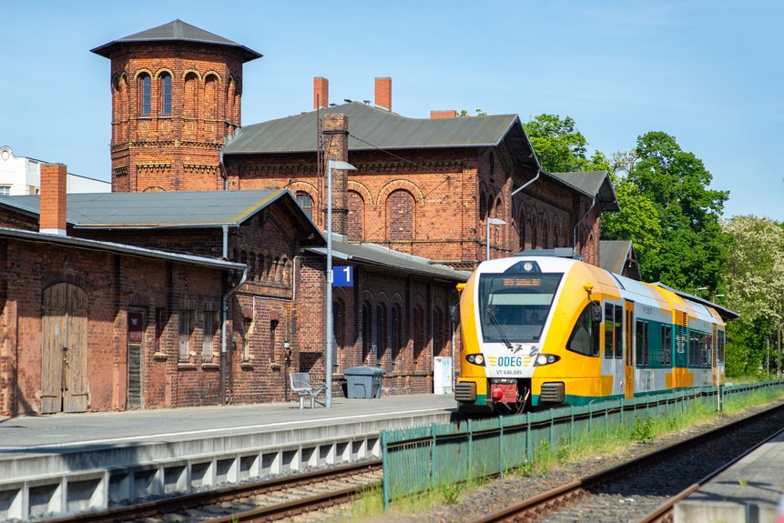 Bahnhofsgebäude mit haltendem Zug an Gleis 1