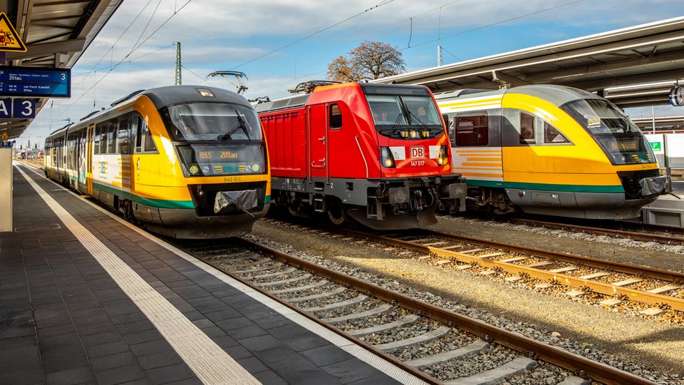 Im Bahnhof stehen zwei Züge der ODEG neben einem Zug der Deutschen Bahn