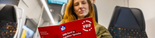 Junge Frau liest Broschüre VBB-Tarif in leichter Sprache.