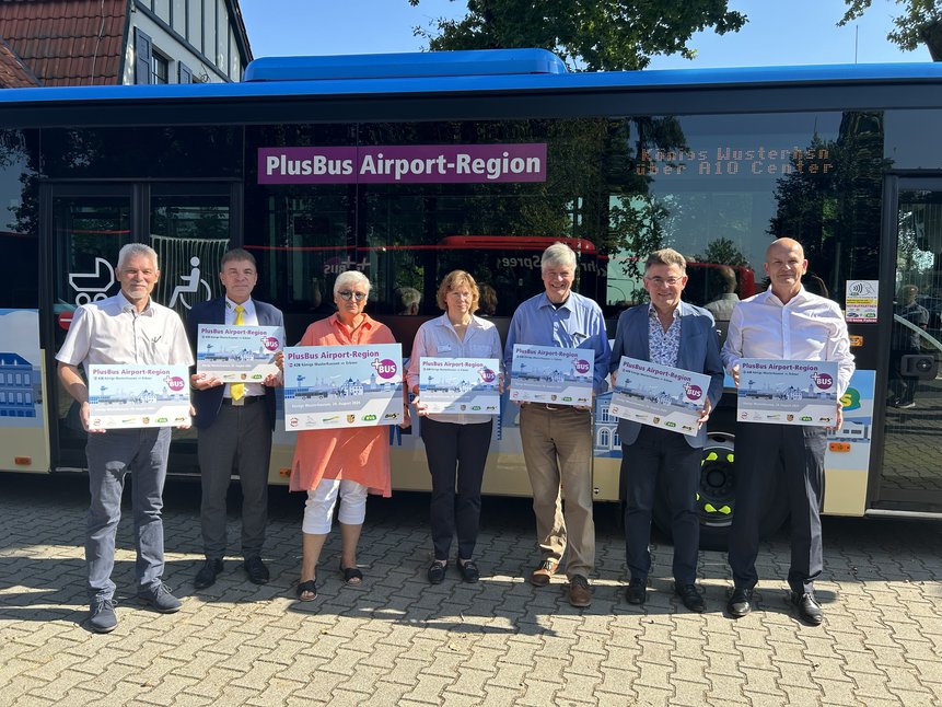 Bild zeigt Menschen vor beklebtem PlusBus